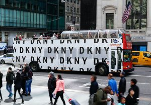 A large DKNY advertisement on a city building with people walking by.